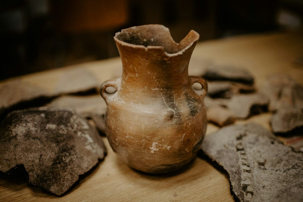 Vase antique en terre cuite posé parmi des tessons de céramique archéologique